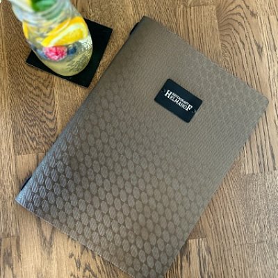 Menu karta s gravírovaním loga na čiernom oceľovom štítku.